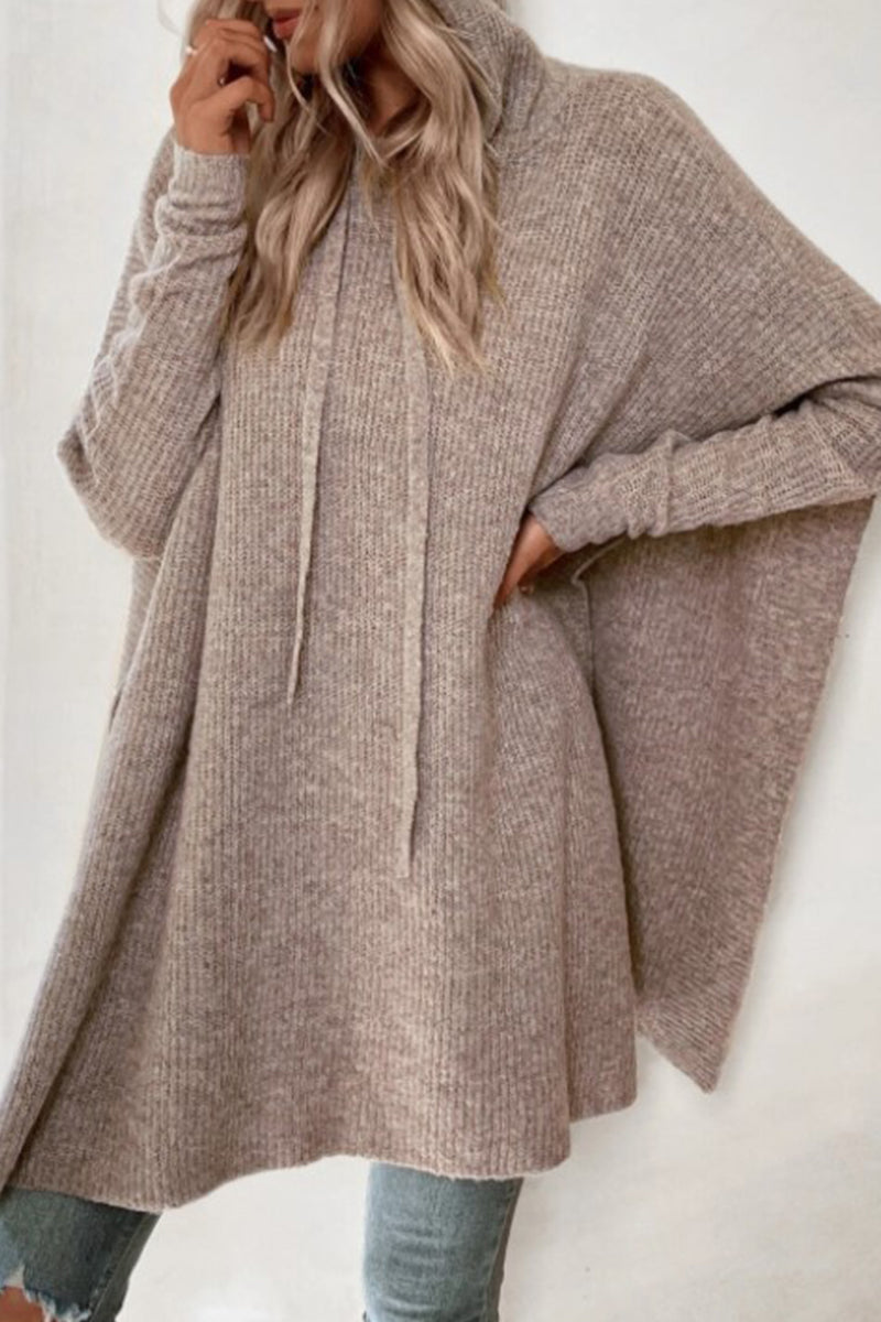 Close-up of a woman wearing a beige knit poncho, showing the texture and drawstring.