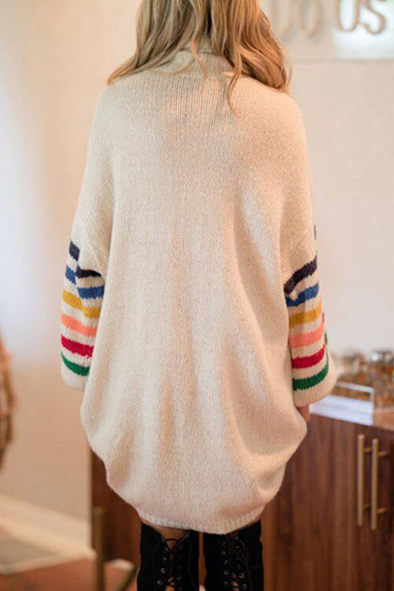Back view of a woman wearing a cream knit sweater dress with colorful stripes on the sleeves