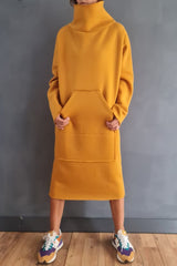 Woman wearing a yellow hooded dress with pockets and colorful sneakers.