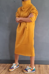 Woman wearing a yellow hooded dress with pockets, arms crossed, and colorful sneakers.