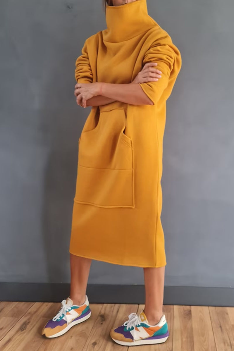 Woman wearing a yellow hooded dress with pockets, arms crossed, and colorful sneakers.