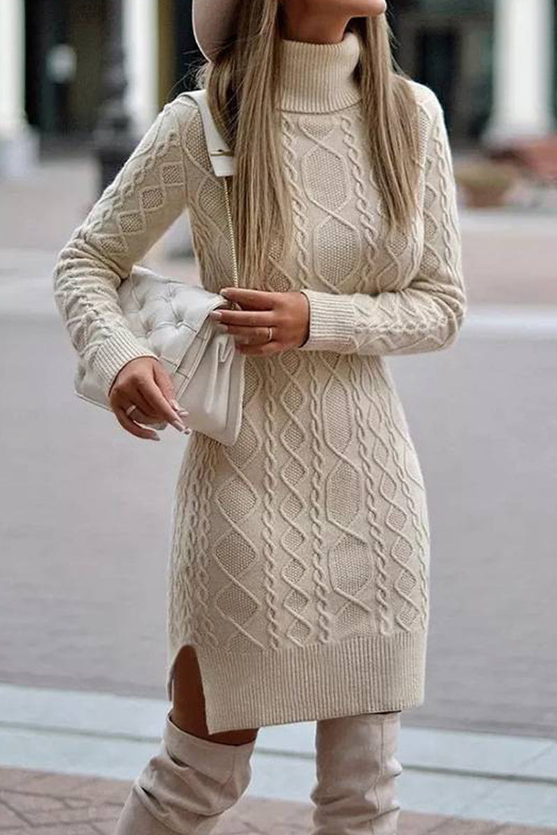 A woman wearing a cream cable knit turtleneck sweater dress with a white handbag.