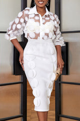 Woman wearing a white sheer polka dot blouse and a white pencil skirt with appliqué details