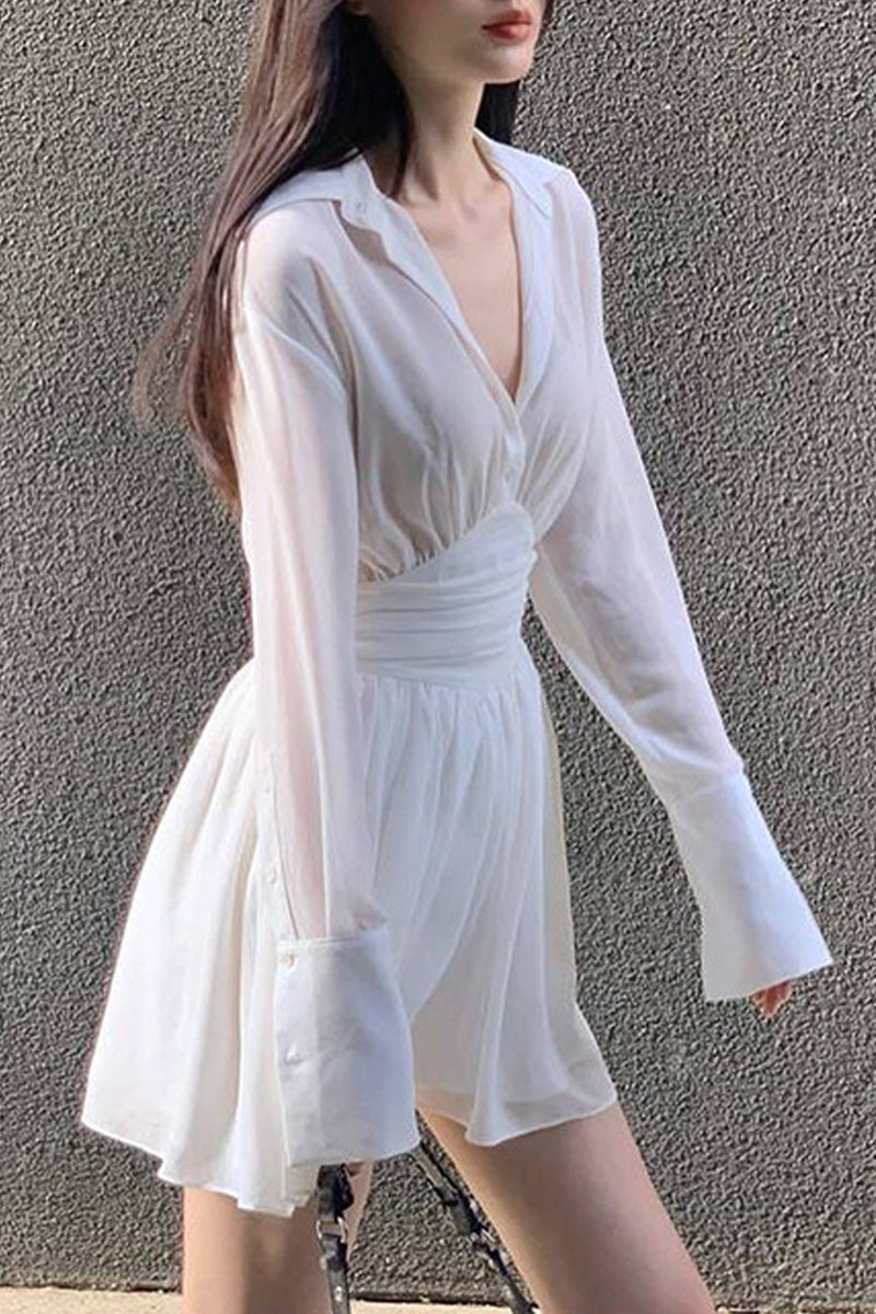 A woman wearing a white sheer dress with a cinched waist and flared sleeves.