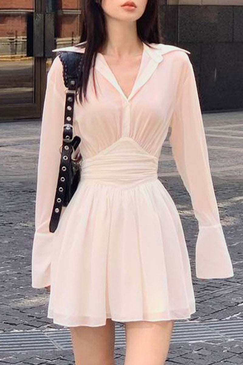 A woman wearing a light pink sheer dress with a cinched waist and flared sleeves.