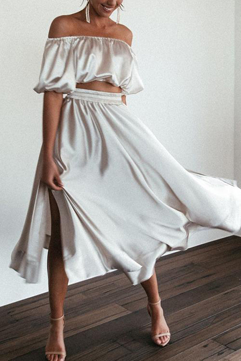 A woman in a flowing silver satin two-piece set twirls, showing off the skirt's movement.