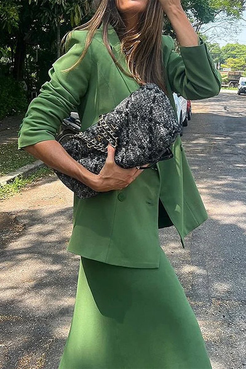 Woman in a green outfit holding a black and white textured clutch