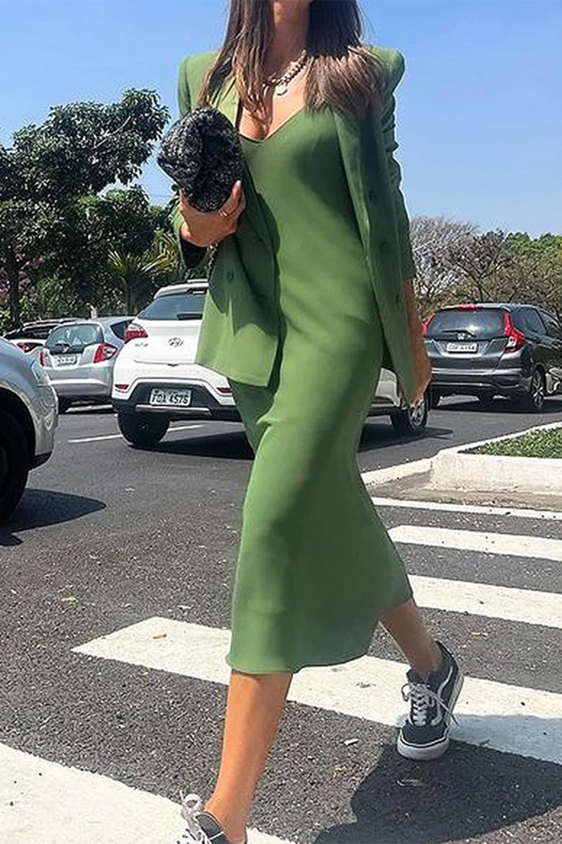 Woman in a green midi dress and blazer walking across a crosswalk