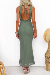Woman wearing a sage green maxi dress with a sheer mesh neckline and ruched bust, shown from the back with a low tie detail.