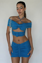 woman wearing a blue ruched crop top and mini skirt with hoop earrings