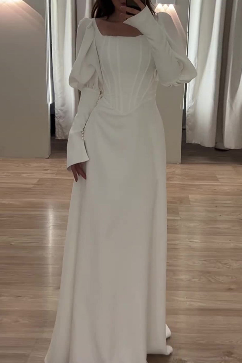 A woman poses in a white dress with a corset bodice and long sleeves.