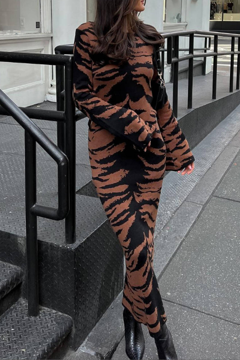 A woman wearing a long-sleeved, tiger-print midi dress.