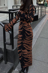 Woman in a tiger-print midi dress standing on stairs.