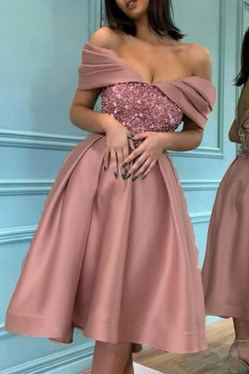 Back view of a woman in a rose gold off-the-shoulder cocktail dress with a sequined bodice and a pleated A-line skirt.