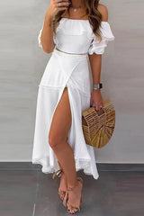 Woman wearing a white off-the-shoulder dress with a high slit and ruffled sleeves