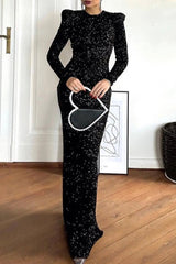 A woman holding a heart-shaped purse in front of a black sequined dress.