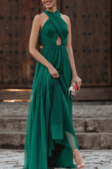 A woman in a green floor-length halter dress, posing elegantly.
