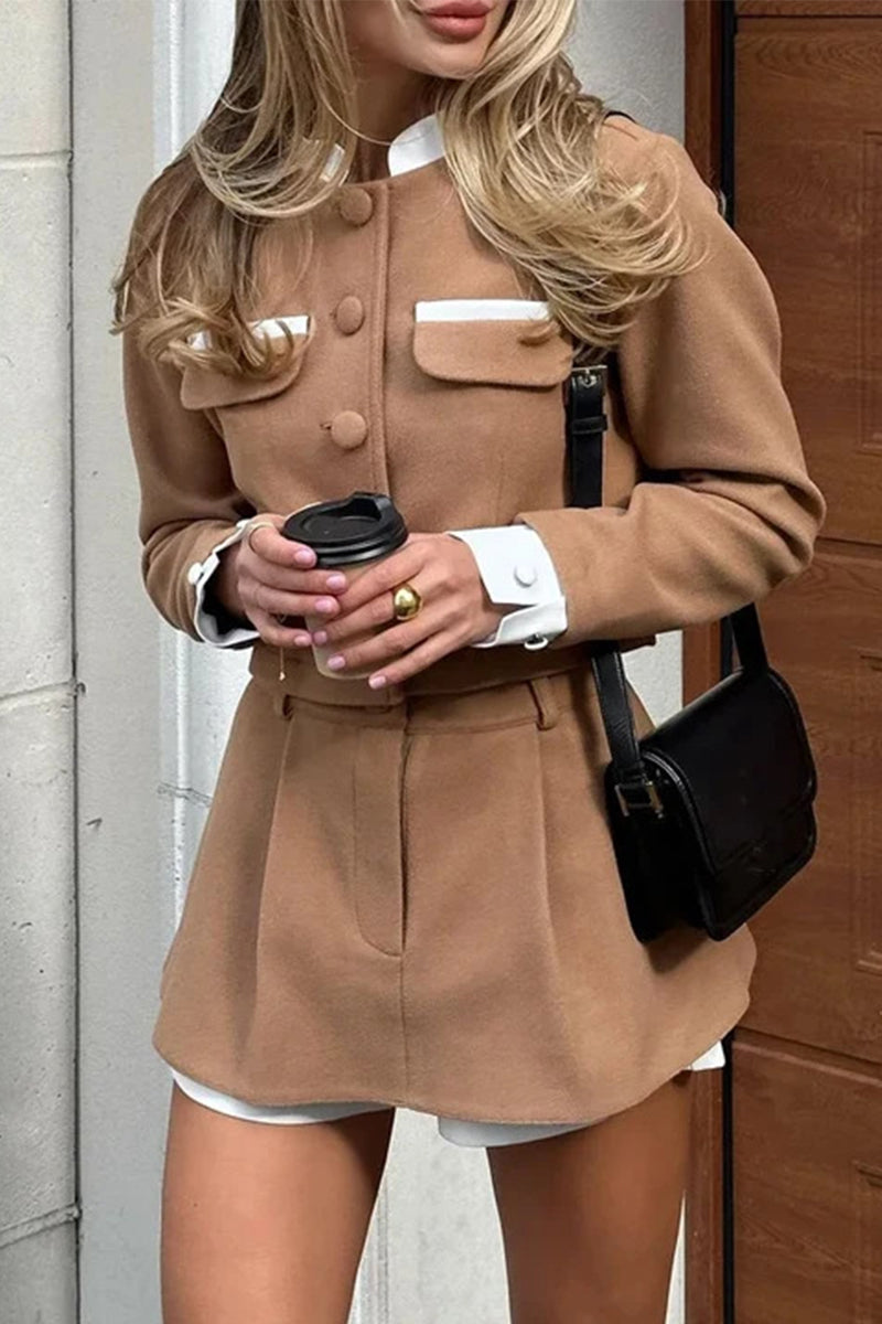 Woman wearing a brown cropped jacket and skirt set with white trim, holding a coffee cup.