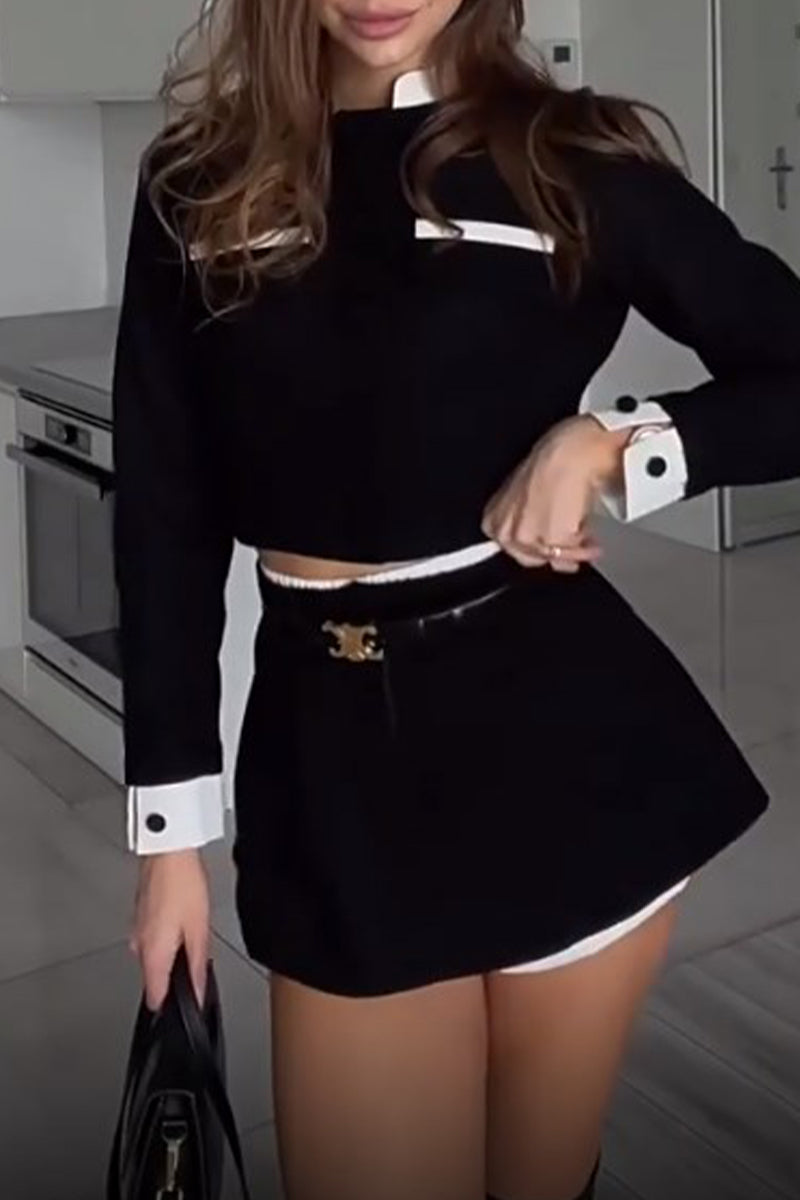 Woman in a black cropped jacket and skirt set with white trim, showing off the belt.