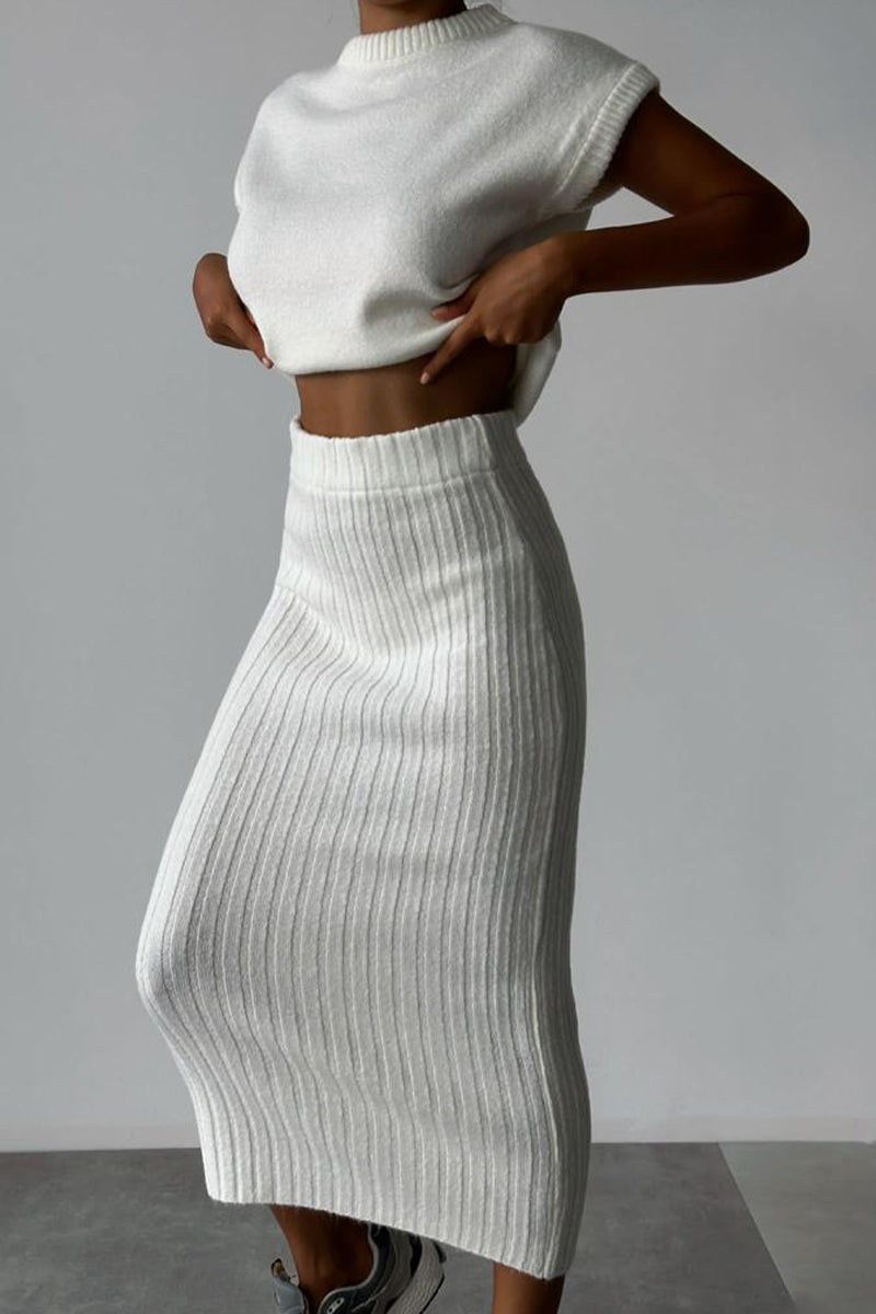 A woman wearing a white ribbed knit sleeveless top and a white ribbed knit midi skirt.