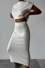 A woman wearing a white ribbed knit sleeveless top and a white ribbed knit midi skirt.