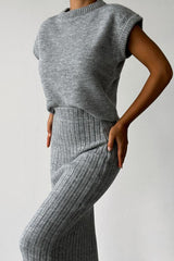Close-up of a woman wearing a grey ribbed knit sleeveless top and a grey ribbed knit midi skirt.