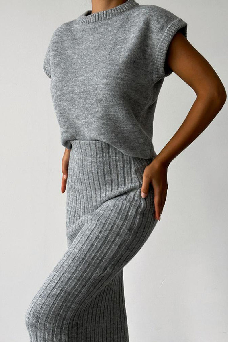 Close-up of a woman wearing a grey ribbed knit sleeveless top and a grey ribbed knit midi skirt.