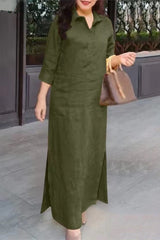 A woman stands wearing a long green dress with a collared neckline and three-quarter sleeves.