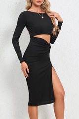 Back view of a woman in a black long-sleeved midi dress with a cut-out and high slit.