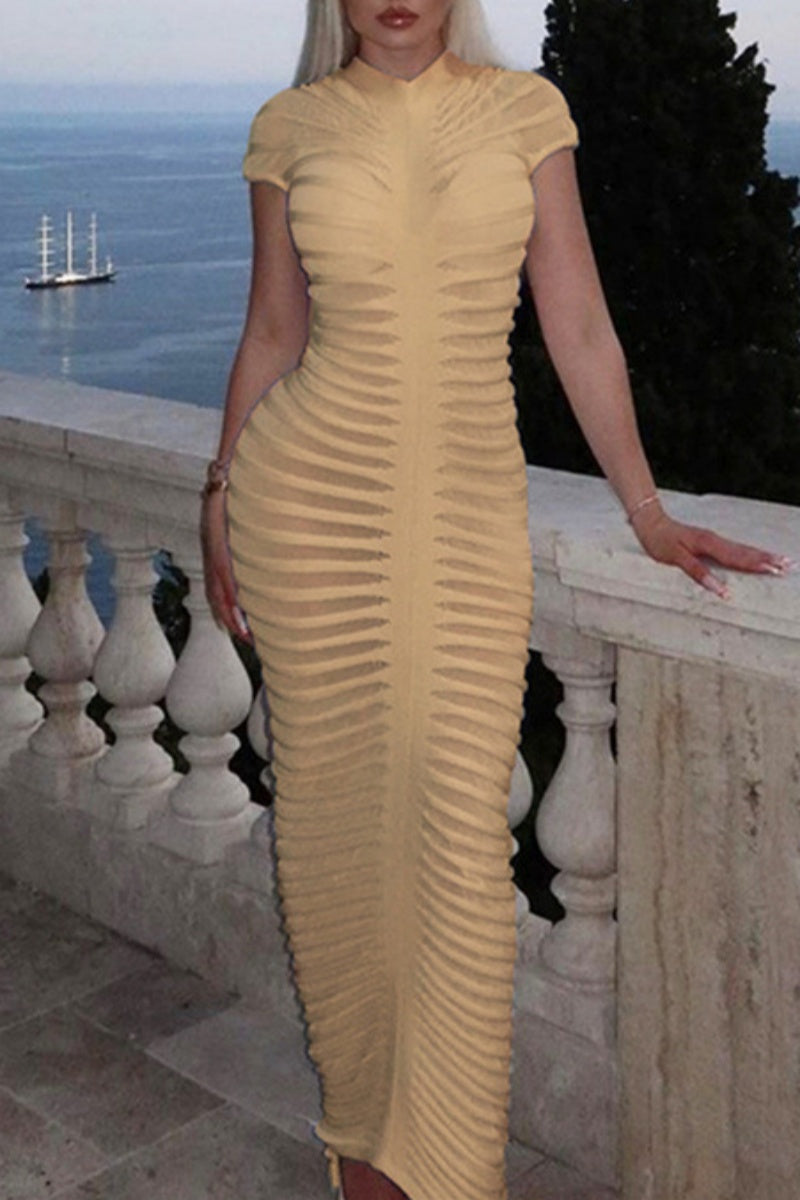 Woman in a beige ribbed bodycon maxi dress with a high neckline and short sleeves, leaning on a railing.