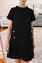Woman wearing a black textured A-line shift dress with short sleeves, a ruffled neckline, and four decorative pockets with button and braided trim.