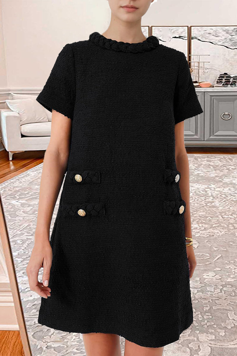 Woman wearing a black textured A-line shift dress with short sleeves, a ruffled neckline, and four decorative pockets with button and braided trim.