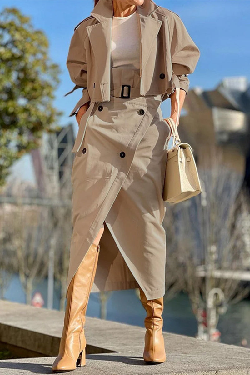 Woman wearing a tan cropped jacket and matching asymmetrical skirt with tan boots and a cream handbag