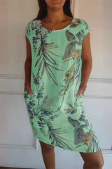 A woman wearing a green floral print cap sleeve dress with pockets.