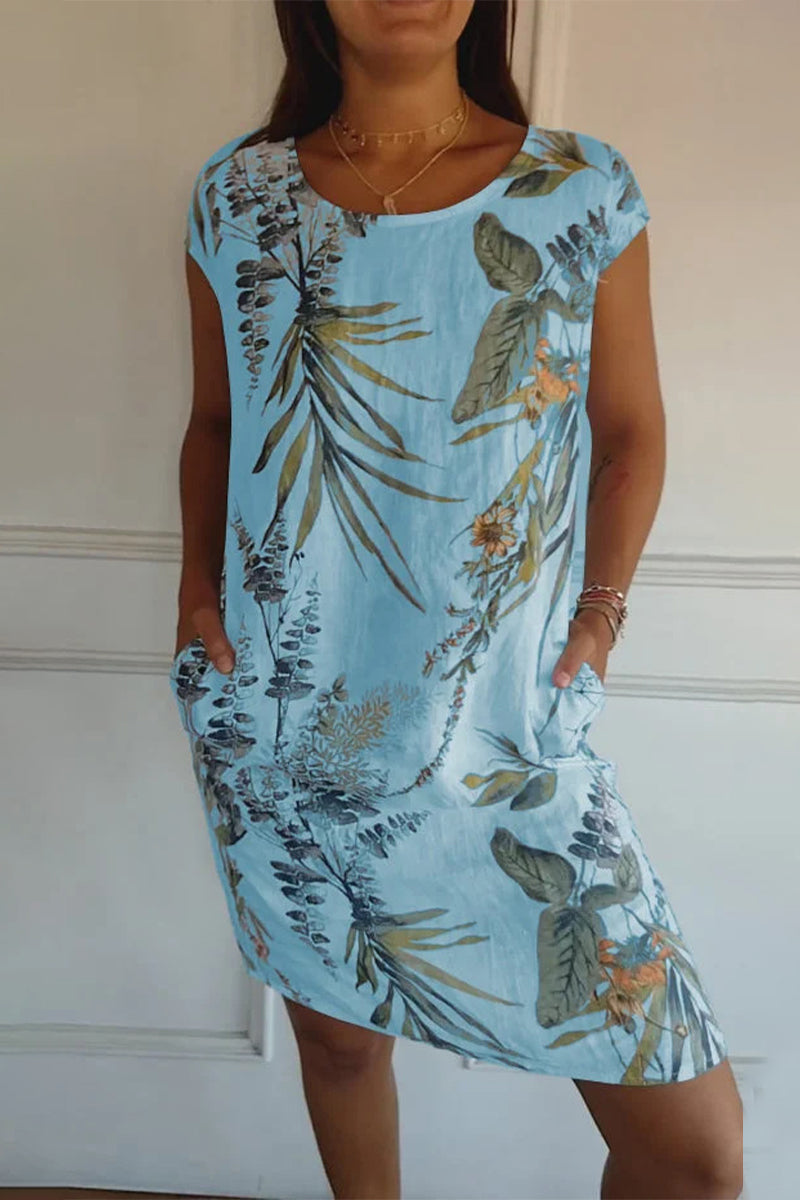 A woman wearing a light blue floral print cap sleeve dress with pockets.