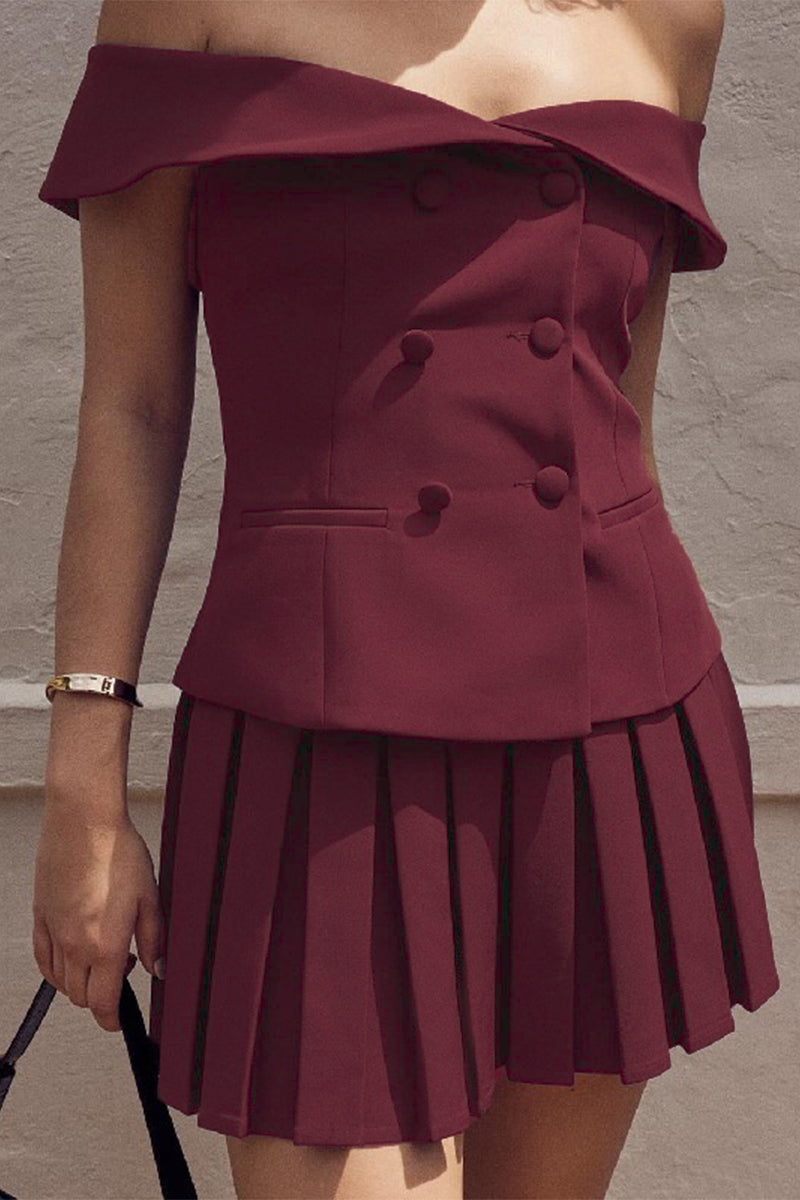 A woman in a maroon off-the-shoulder blazer dress with a pleated skirt, showing the detail of the buttons and pockets.