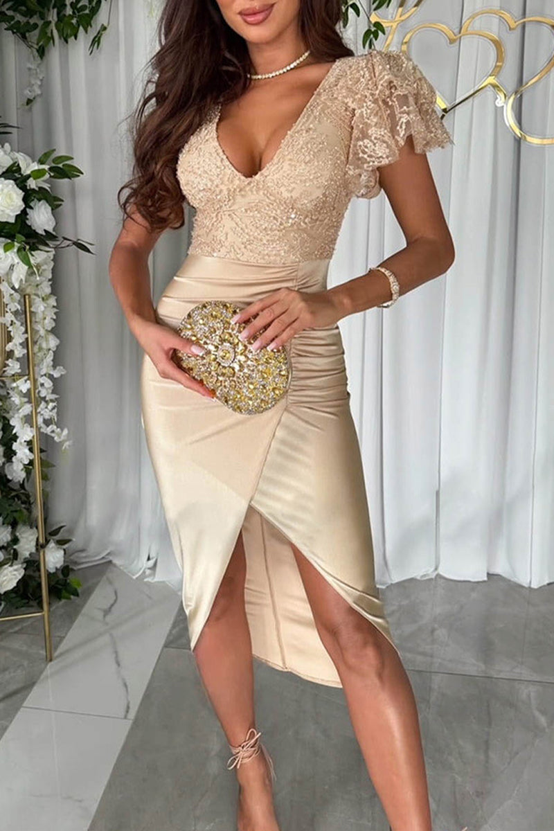 Woman in a gold sequined and lace v-neck dress with a ruched satin skirt and a high slit, holding a gold embellished clutch.