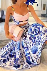 Woman holding a pink knitted accessory and a pink clutch bag while wearing a blue and white floral print crop top and a matching tiered maxi skirt.