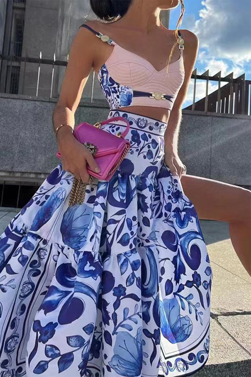 Woman wearing a blue and white floral print crop top and a matching tiered maxi skirt with a pink clutch bag.