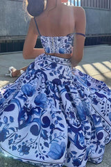 Back view of a woman in a blue and white floral print crop top and a matching tiered maxi skirt, sitting on the ground.