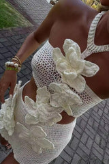 Close-up of a woman wearing a white crochet crop top with floral appliqués and a matching mini skirt.