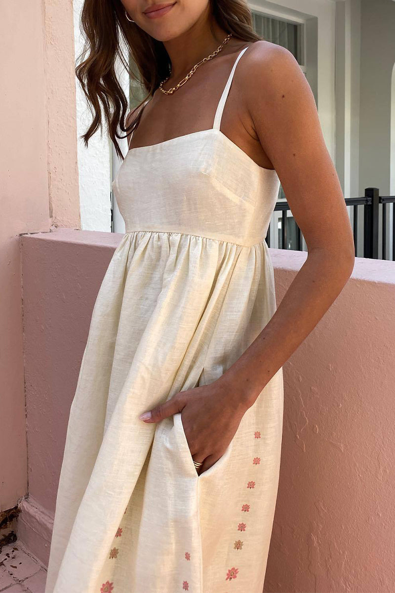 Close-up of a woman's hand in the pocket of a cream maxi dress with pink floral print