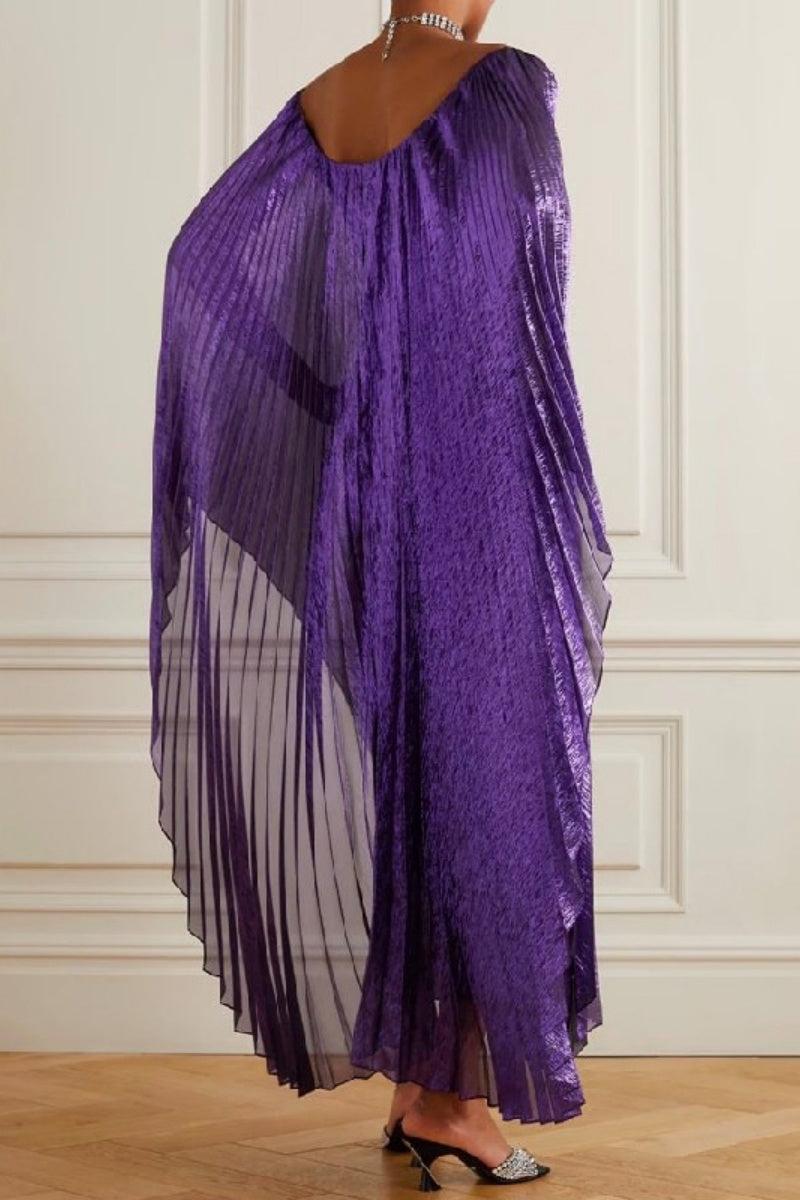 Back view of a woman in a purple metallic pleated maxi dress with dramatic cape sleeves.