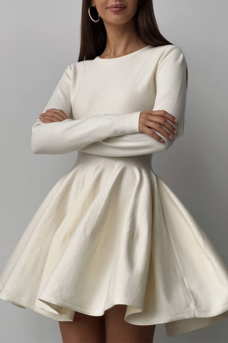 A woman wearing a long-sleeved ivory fit-and-flare dress with her arms crossed.