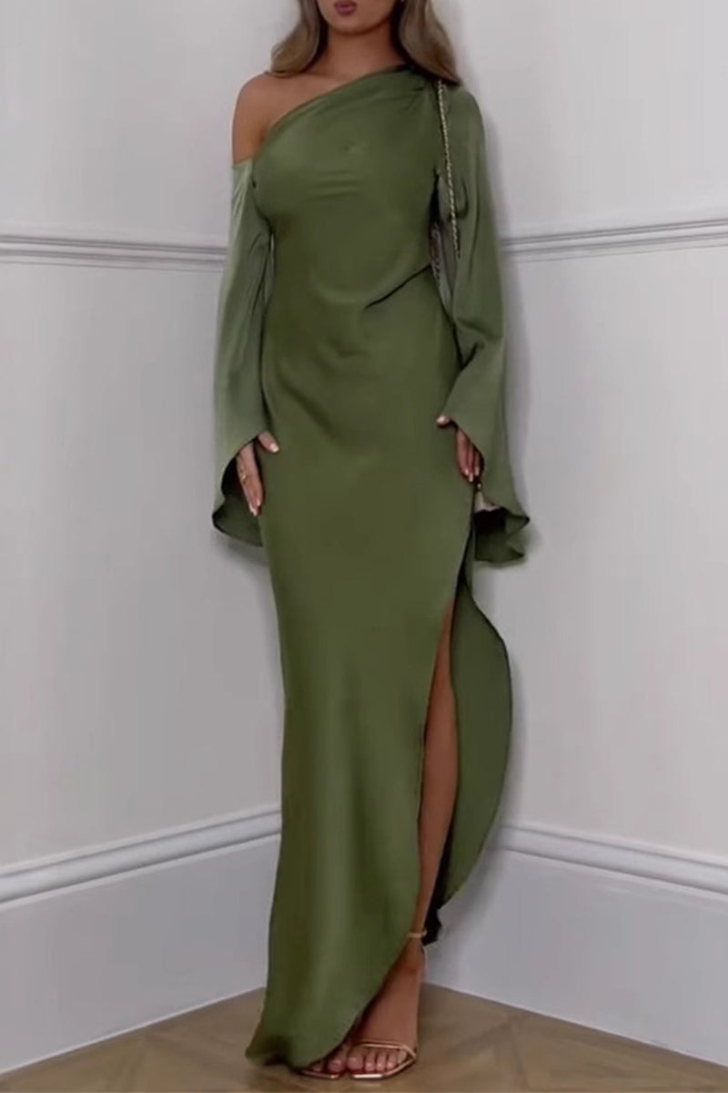 Full-length shot of a woman in an olive green satin gown with an asymmetrical neckline and long, flared sleeves. The dress has a high slit, and she is accessorized with a gold chain bag.