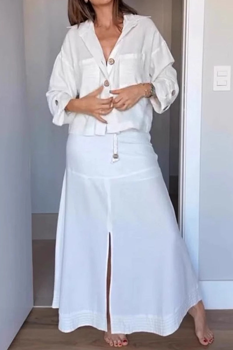 Woman wearing a white linen-like button-down shirt and a matching white maxi skirt with a front slit.