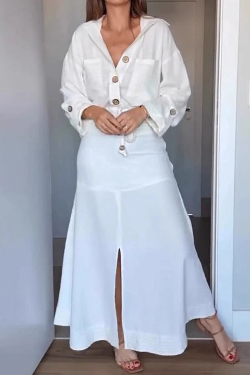 Woman wearing a white linen-like button-down shirt and a matching white maxi skirt with a front slit, showing the full outfit.