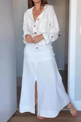 Woman wearing a white linen-like button-down shirt and a matching white maxi skirt with a front slit, highlighting the outfit's flow.