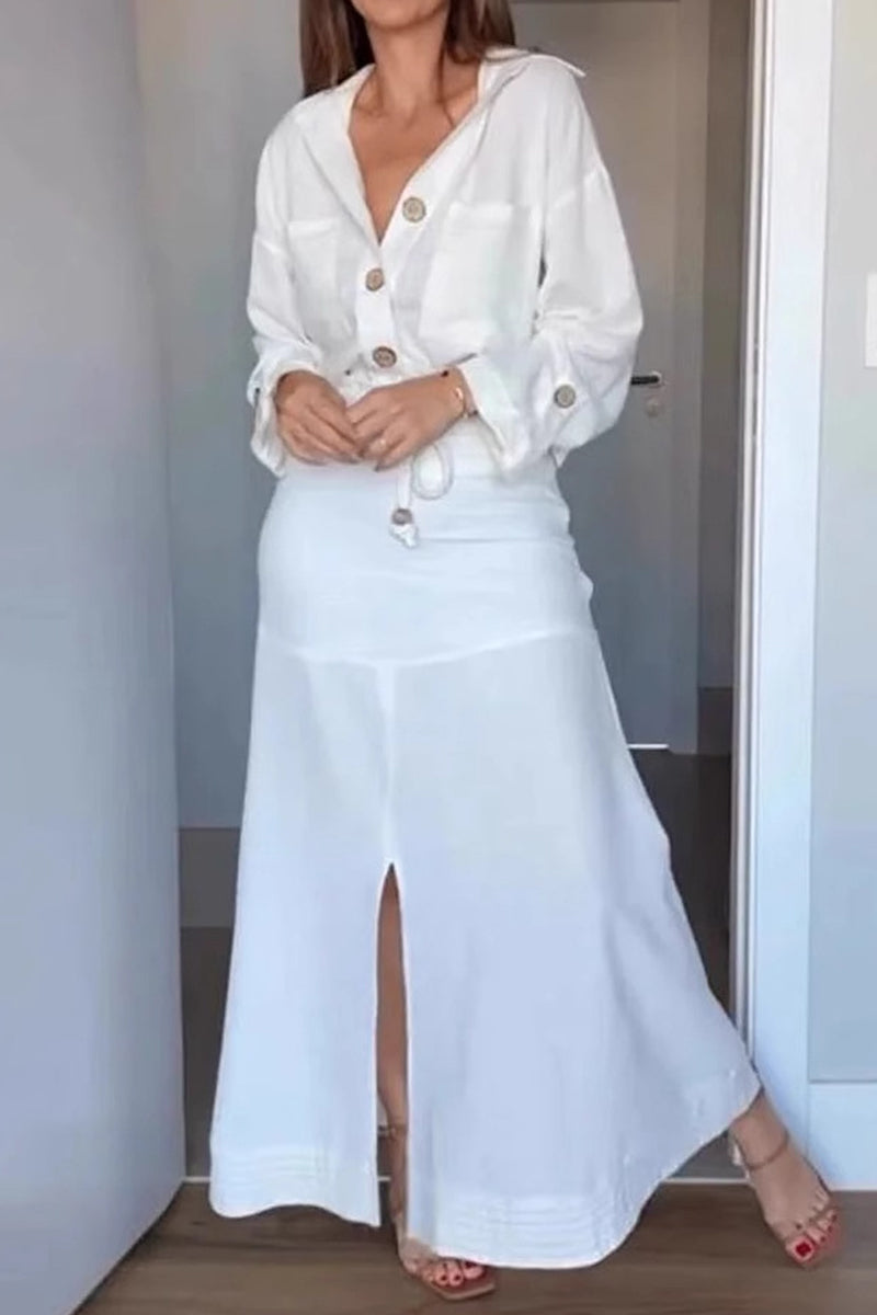 Woman wearing a white linen-like button-down shirt and a matching white maxi skirt with a front slit, highlighting the outfit's flow.