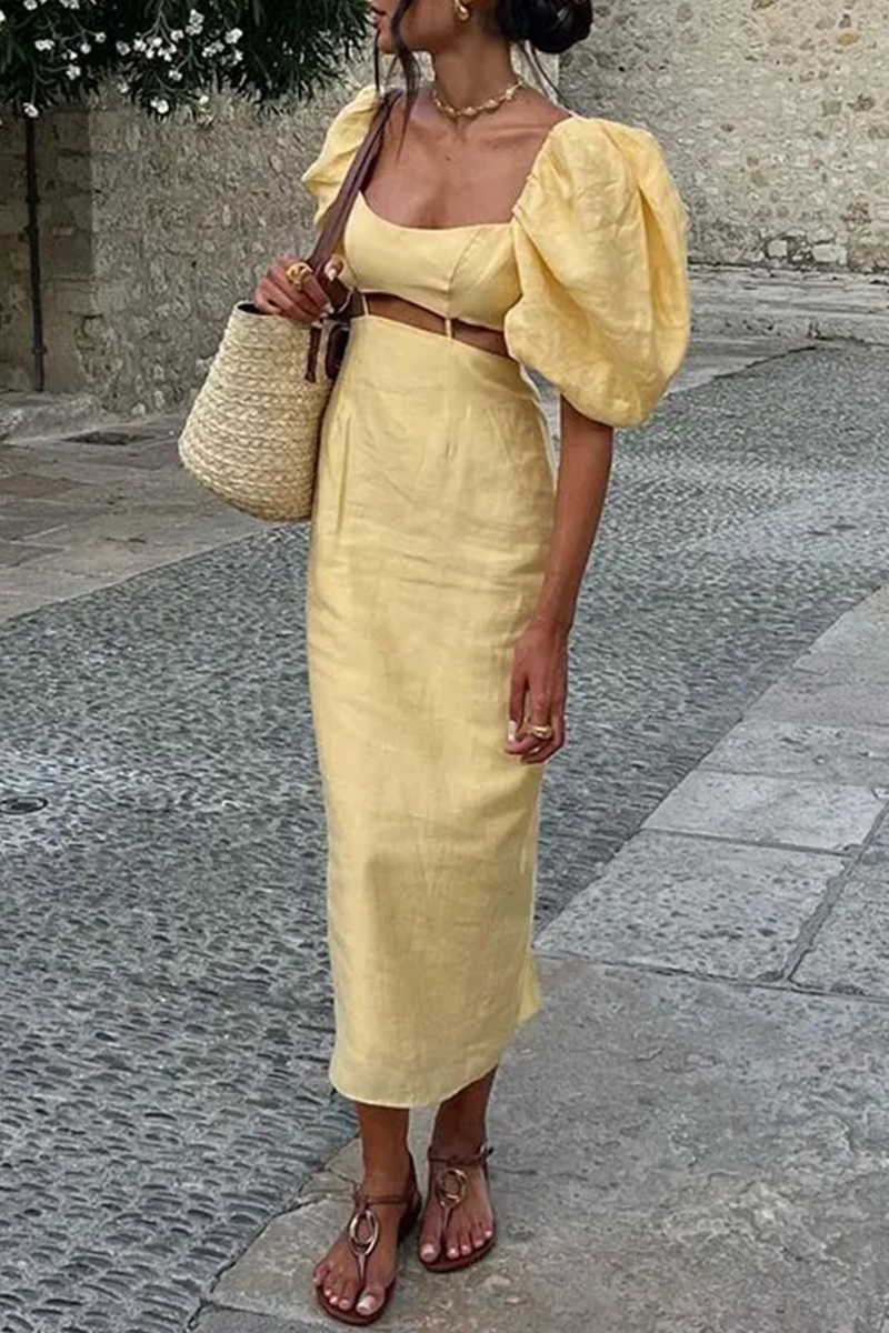 A woman wearing a yellow linen dress with puff sleeves and a cut-out detail, holding a straw bag.